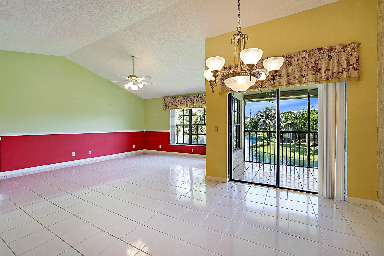 A bright, tiled living and dining area features a vaulted ceiling, chandelier, and balcony view — 3283 Jog Park Drive, FL 33467, FL