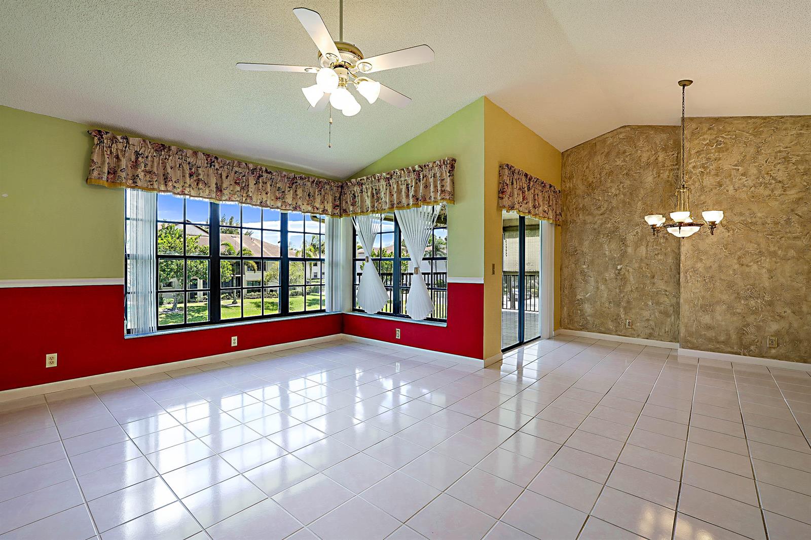 A bright, tiled living area features large windows with floral valances and a ceiling fan — 3283 Jog Park Drive, FL 33467, FL