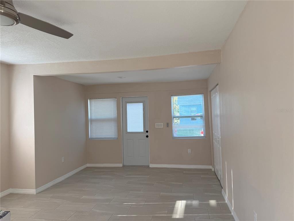 A room with light-colored walls, tiled flooring, a ceiling fan, a door, and two windows — 1015 23RD AVENUE W, BRADENTON, FL