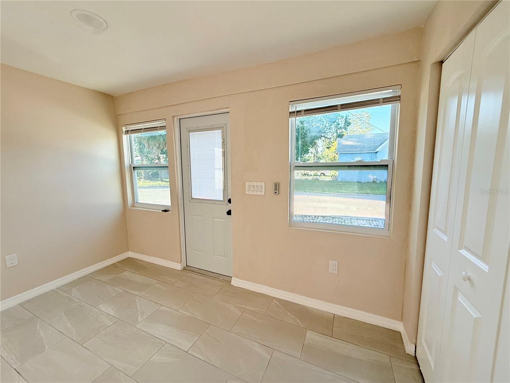 A room with light-colored walls, tiled flooring, a central door, and two windows — 1015 23RD AVENUE W, BRADENTON, FL