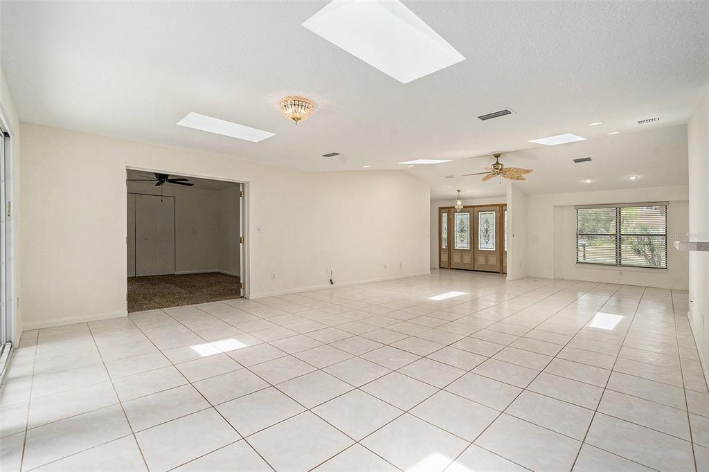 A spacious, tiled living room features a vaulted ceiling with multiple skylights and double doors — 2057 BRENT PLACE, PALM HARBOR, FL