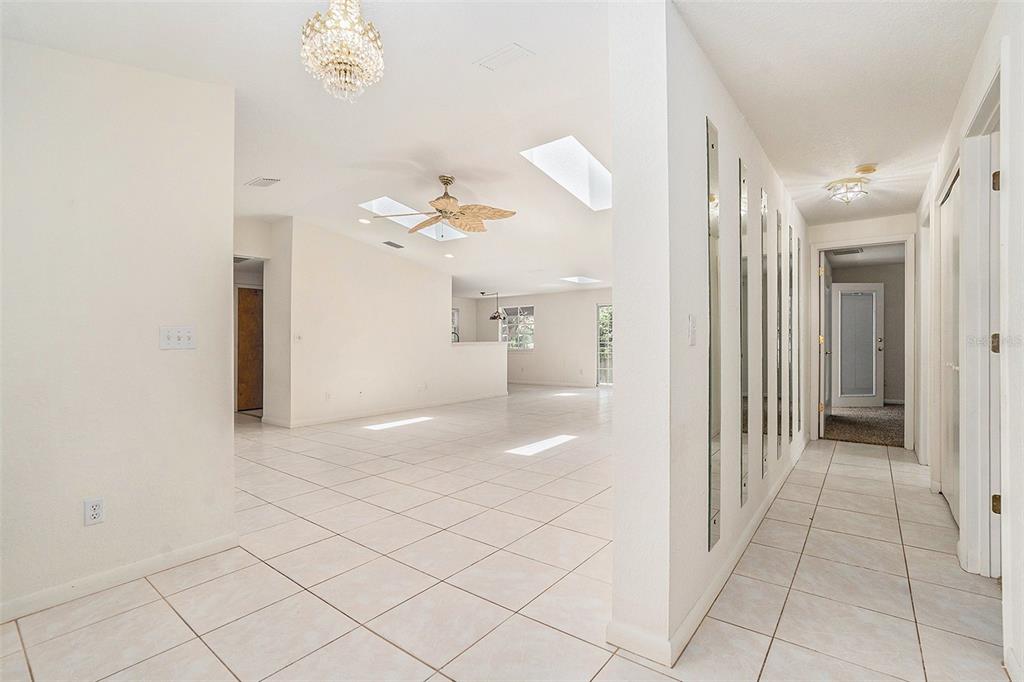 A bright, tiled living area features a vaulted ceiling with skylights and a mirrored hallway — 2057 BRENT PLACE, PALM HARBOR, FL