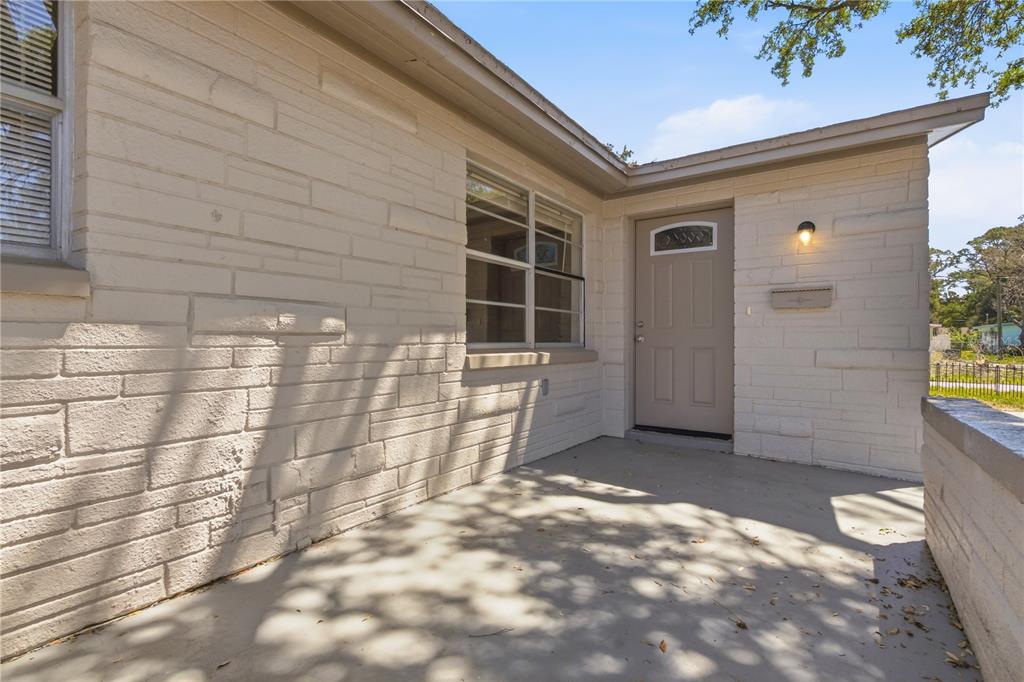 A beige brick exterior features a front porch, a single door, and a window — 4941 AMHERST COURT, NEW PORT RICHEY, FL