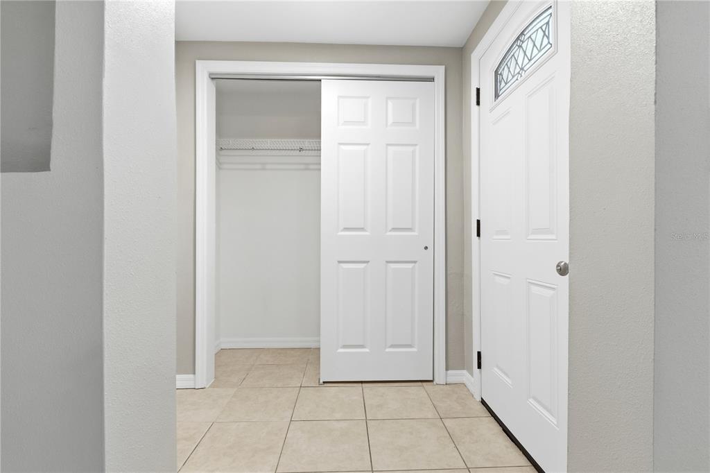 A tiled entryway features a white sliding closet door and a white front door — 4941 AMHERST COURT, NEW PORT RICHEY, FL