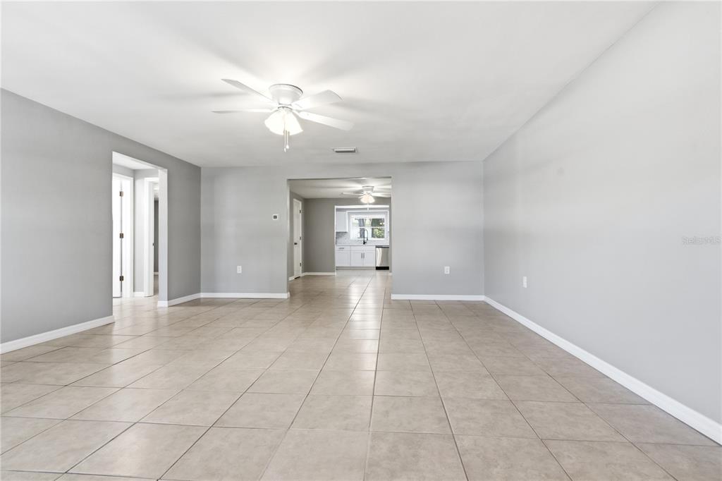 An empty room with light gray walls, tile flooring, and a ceiling fan — 4941 AMHERST COURT, NEW PORT RICHEY, FL