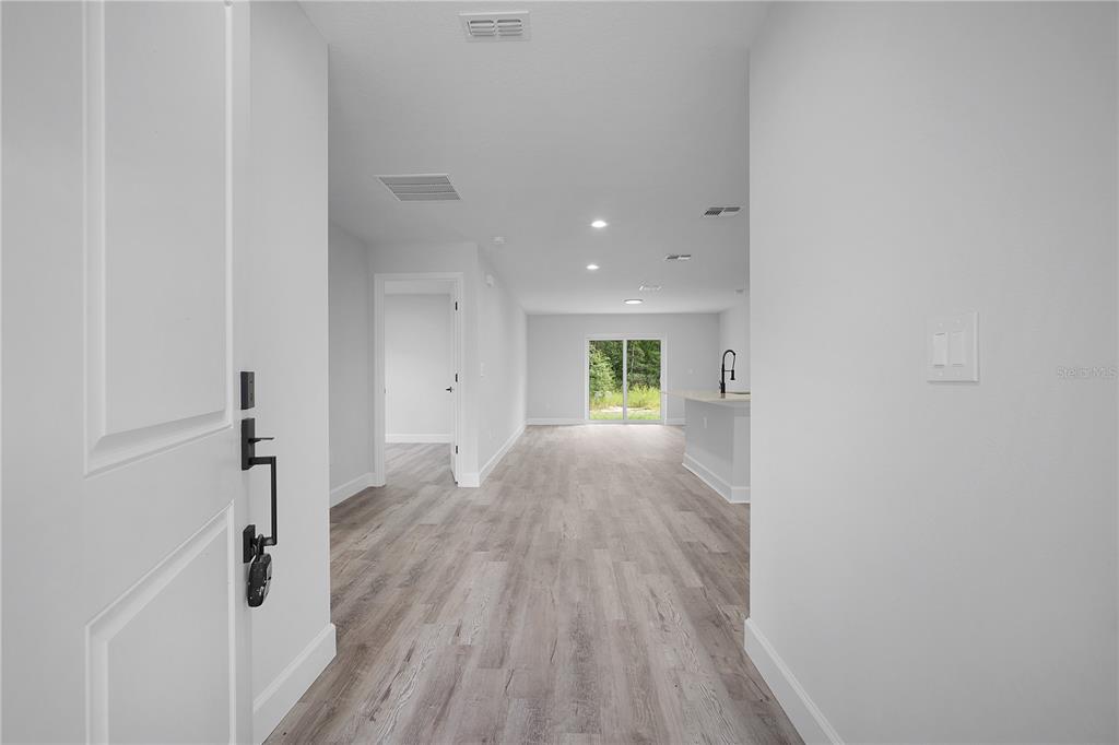 An interior view shows a hallway leading to an open-concept kitchen and living area — 13969 SW 45TH TERRACE, OCALA, FL