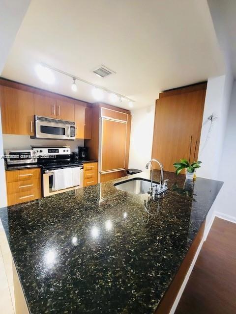 A kitchen features wood cabinets, a dark granite island, and stainless steel appliances — 10275 Collins Ave # 327, Bal Harbour FL 33154, BAL HARBOUR, FL