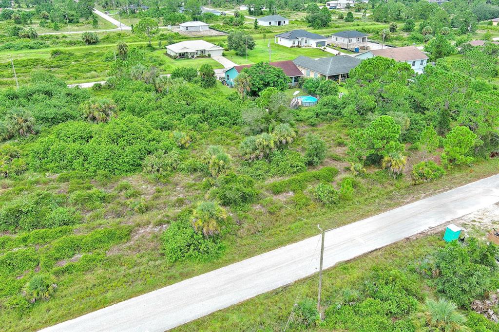 An aerial view shows a dirt road bordering a large, undeveloped lot with scattered vegetation — 928 NORFOLK AVENUE S, LEHIGH ACRES, FL