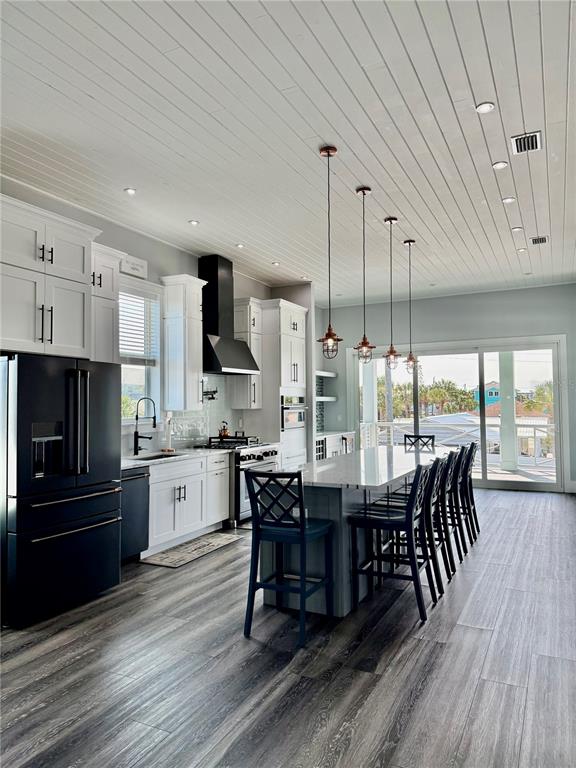 A modern kitchen features white cabinetry, a large island with bar stools, and wood-look flooring — 304 N 7TH STREET, FLAGLER BEACH, FL