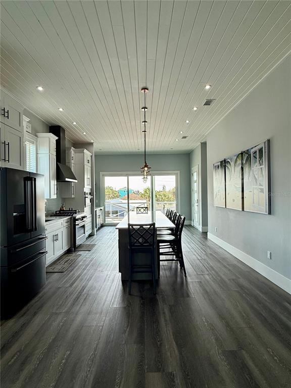 A kitchen and dining area features a long island, white cabinetry, and wood-look flooring — 304 N 7TH STREET, FLAGLER BEACH, FL