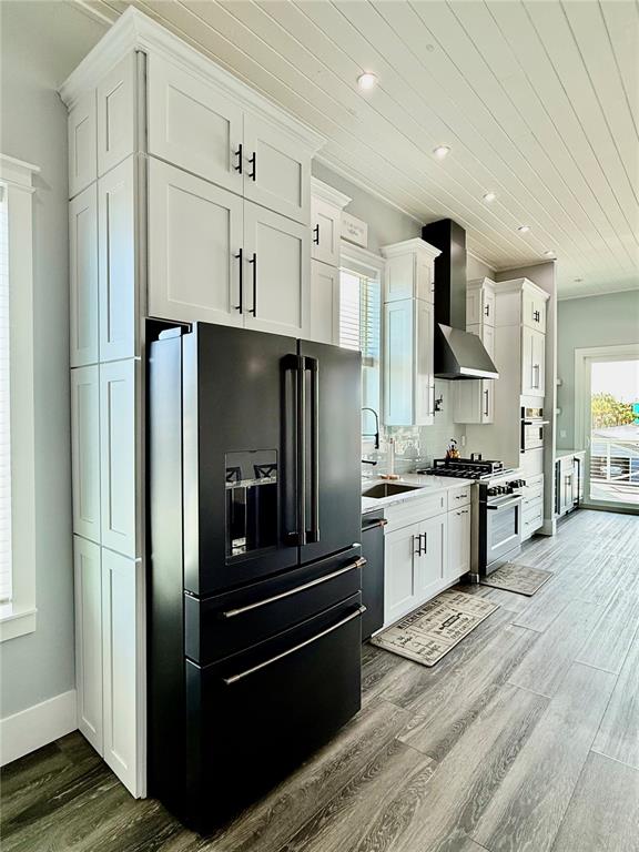 A modern kitchen features white cabinetry, a black refrigerator, and wood-look flooring — 304 N 7TH STREET, FLAGLER BEACH, FL