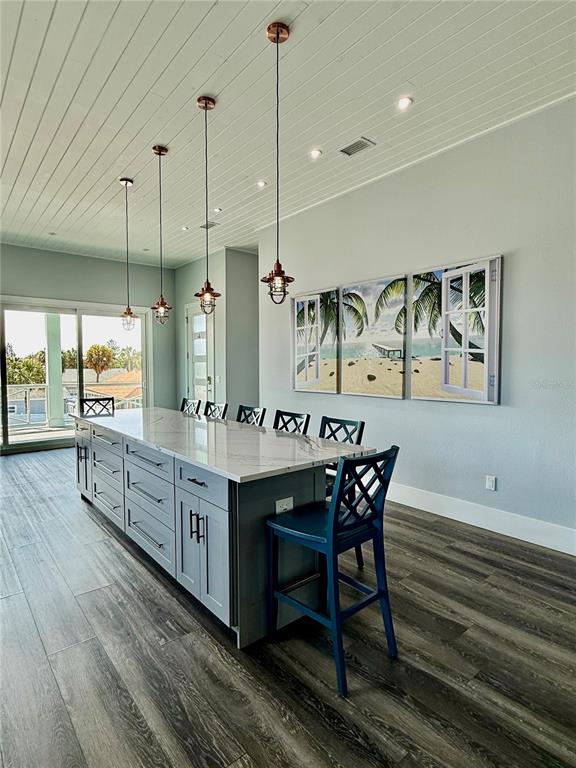 A kitchen island with blue cabinets and white countertops sits beneath four hanging pendant lights — 304 N 7TH STREET, FLAGLER BEACH, FL