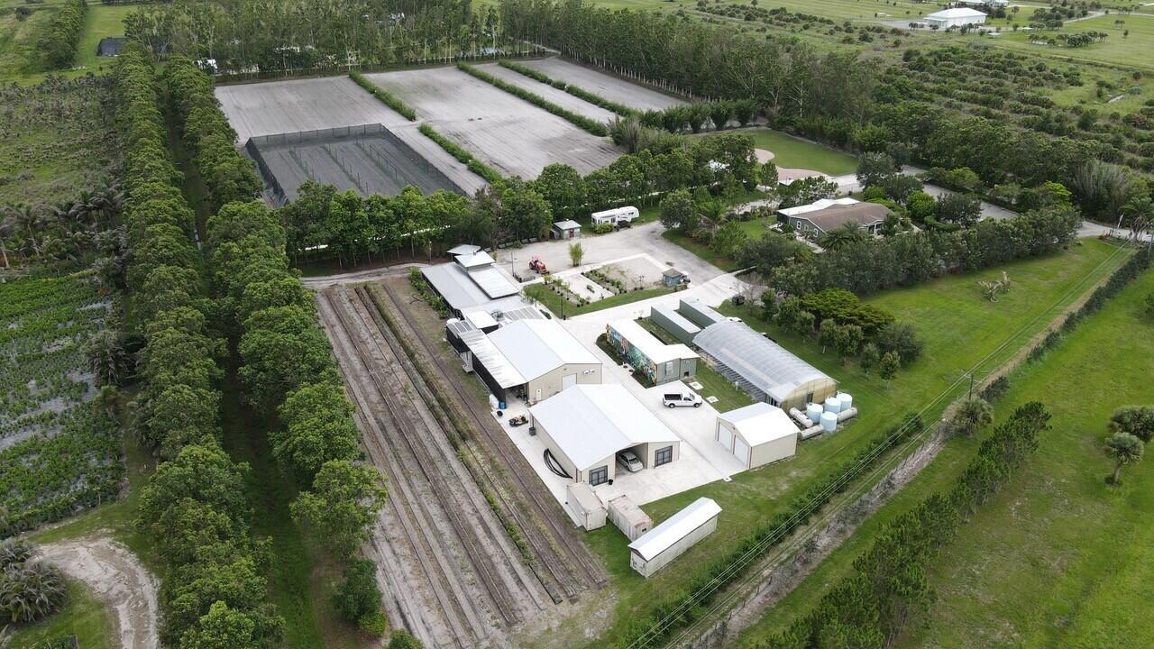 An aerial view shows a rural property with multiple buildings, greenhouses, and agricultural fields — 8006 SW Kanner Highway, FL 34956, FL