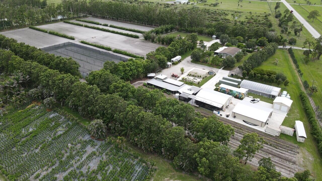 An aerial view shows a rural property with greenhouses, agricultural fields, and several outbuildings — 8006 SW Kanner Highway, FL 34956, FL
