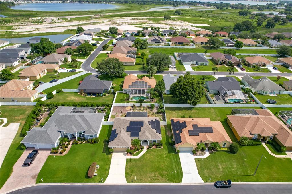 An aerial view shows a suburban neighborhood with houses, swimming pools, and solar panels — 301 TERRANOVA BOULEVARD, WINTER HAVEN, FL