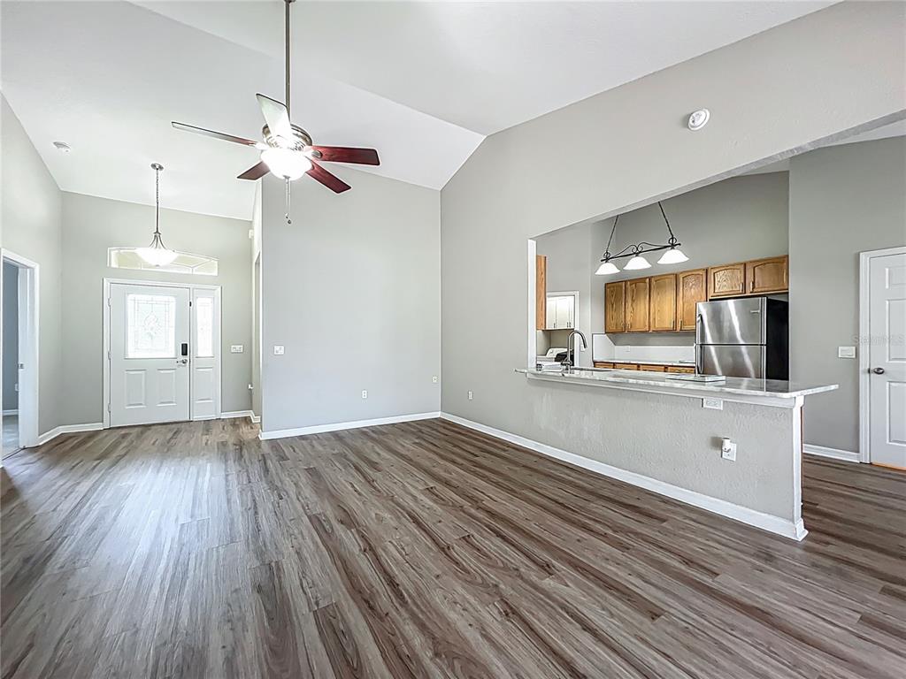 An open-concept living area features vaulted ceilings, wood-look flooring, and a kitchen pass-through window — 301 TERRANOVA BOULEVARD, WINTER HAVEN, FL