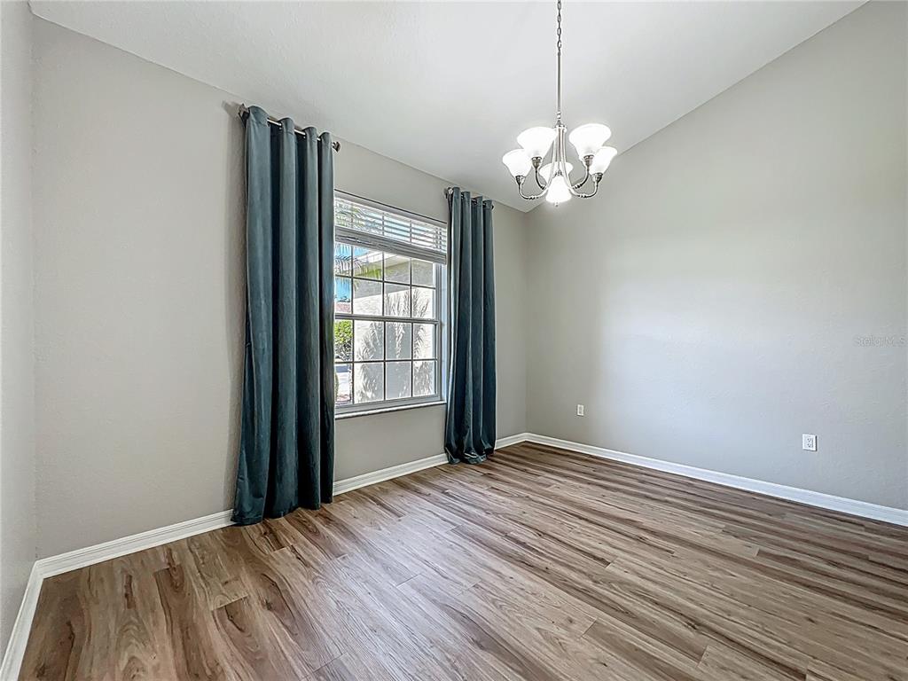A dining room with wood-look flooring, a chandelier, and blue curtains over a window — 301 TERRANOVA BOULEVARD, WINTER HAVEN, FL