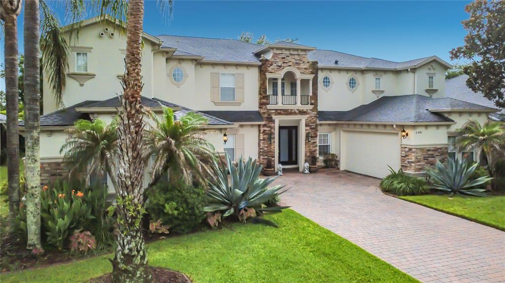 A two-story stucco house with a stone-accented entrance and a paved driveway — 3405 HEIRLOOM ROSE PLACE, OVIEDO, FL