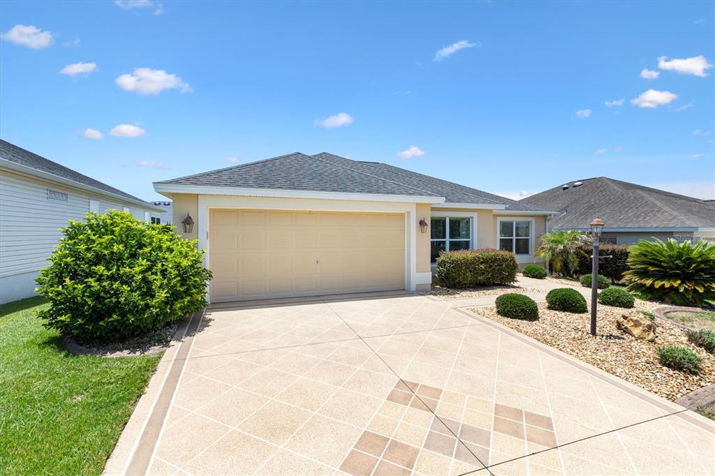 A single-story house with a beige garage door and a patterned concrete driveway — 3104 BLACKSTOCK WAY, THE VILLAGES, FL