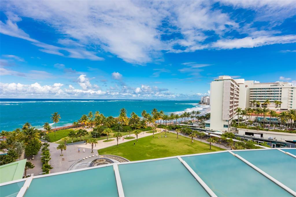 An elevated view of a coastal park, beach, and hotel buildings under a blue sky — 1052 ASHFORD AVENUE UNIT 8A, SAN JUAN, PR