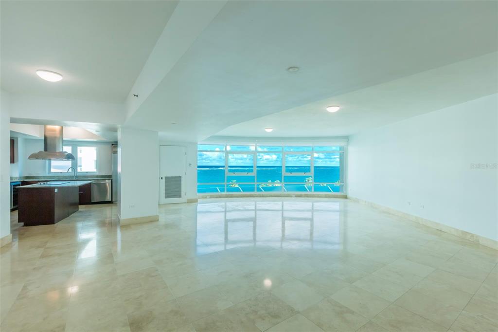 An open-concept living area with light tile floors and floor-to-ceiling windows overlooking the ocean — 1052 ASHFORD AVENUE UNIT 8A, SAN JUAN, PR