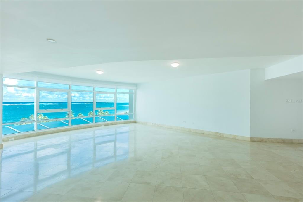 A spacious, empty room with light-colored tile floors and large windows overlooking the ocean — 1052 ASHFORD AVENUE UNIT 8A, SAN JUAN, PR