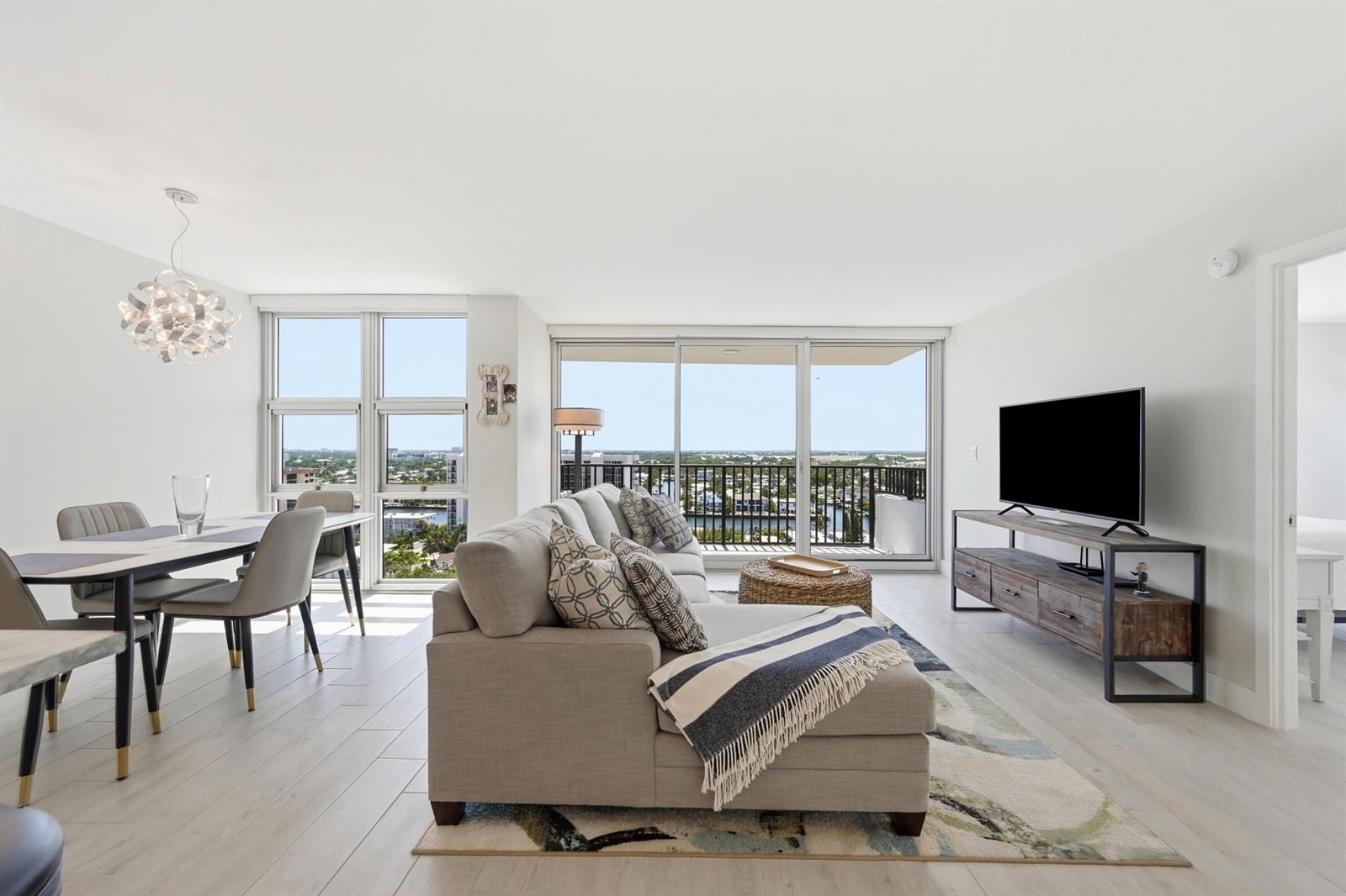 A bright living and dining area features light wood floors, a sectional sofa, and balcony views — 531 N Ocean Boulevard # 1601, Pompano Beach FL 33062, POMPANO BEACH, FL