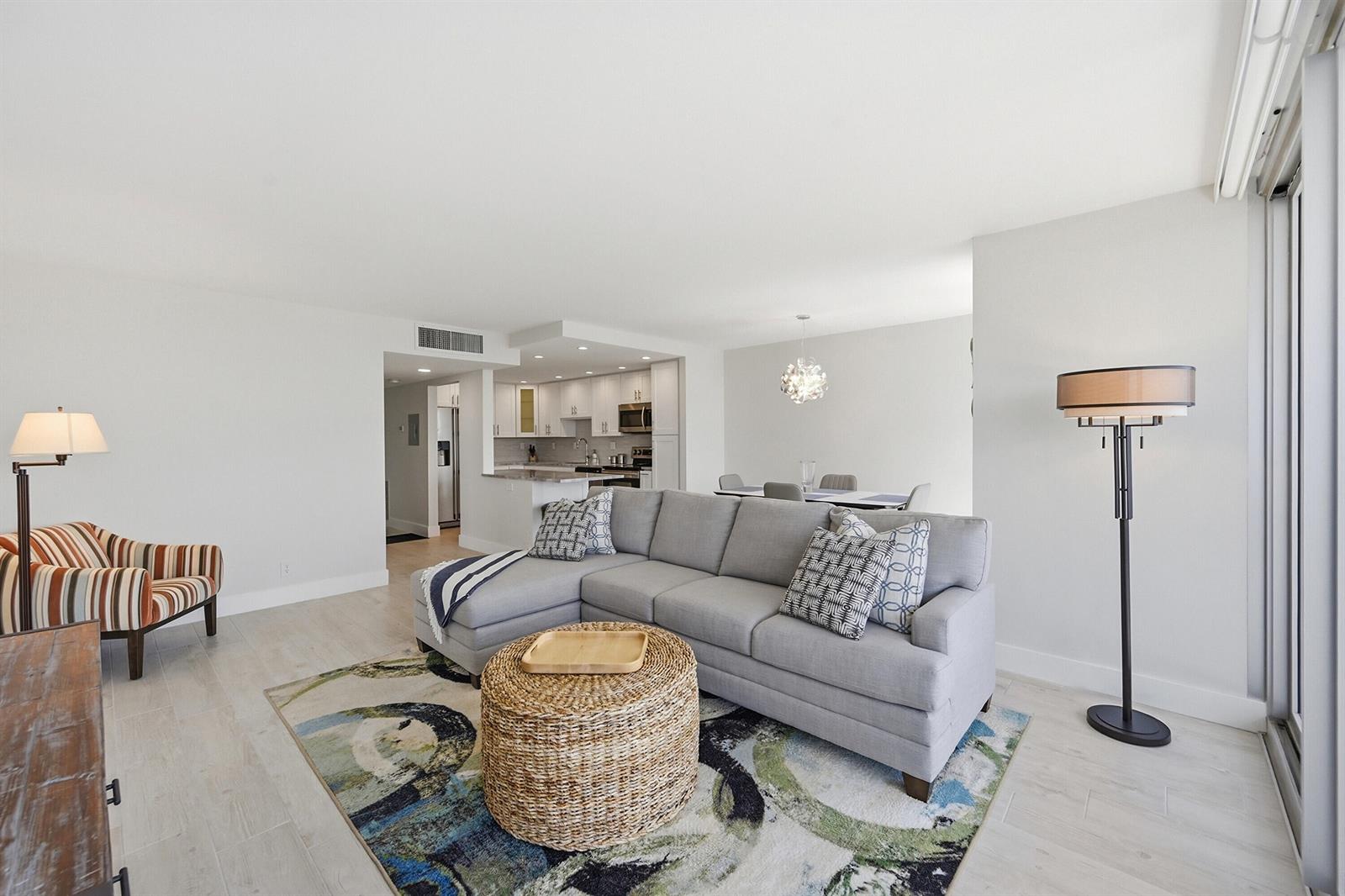 A living room with a gray sectional sofa, patterned area rug, and an open kitchen — 531 N Ocean Boulevard # 1601, Pompano Beach FL 33062, POMPANO BEACH, FL