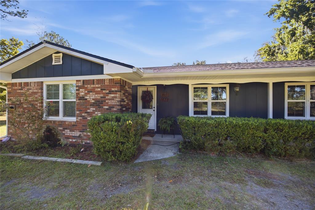 A single-story house features a brick facade, dark blue siding, and a white front door — 1638 SW KING STREET, LAKE CITY, FL