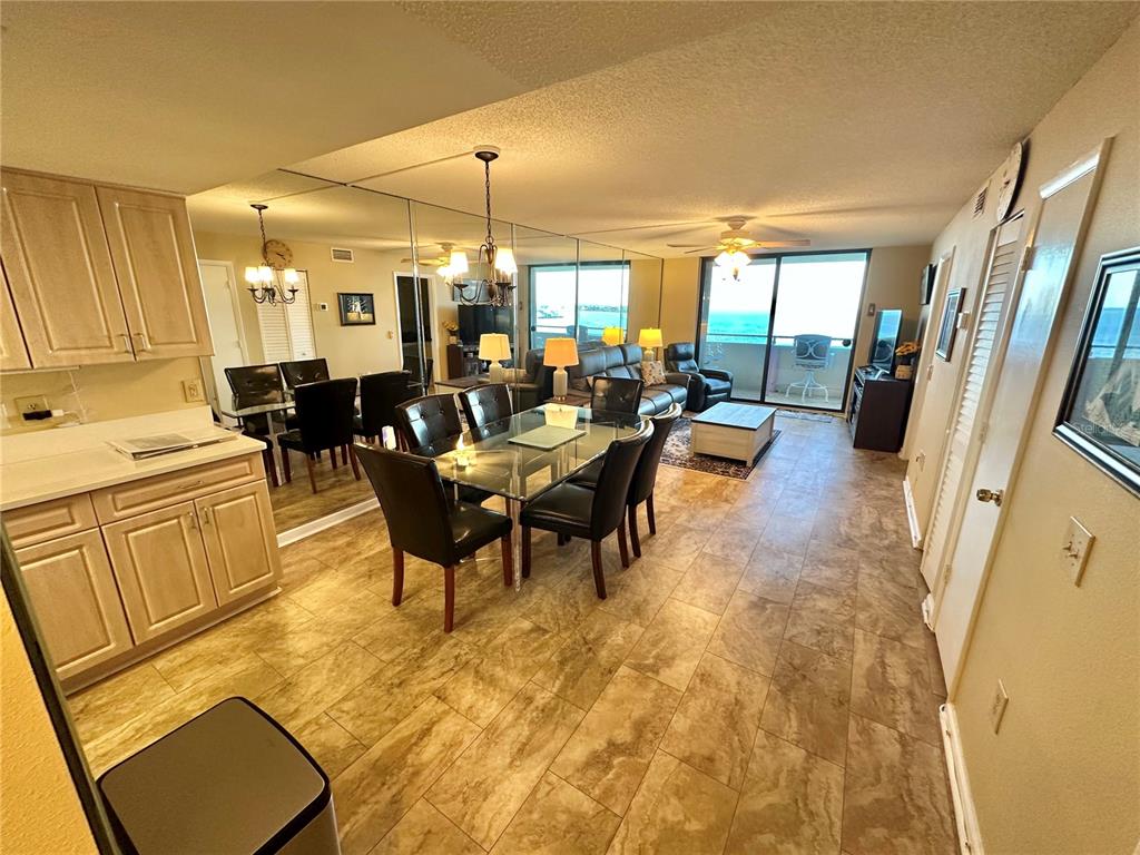 A dining area with a glass table and mirrored wall opens to a living room balcony — 6009 SEA RANCH DRIVE UNIT 707, HUDSON, FL