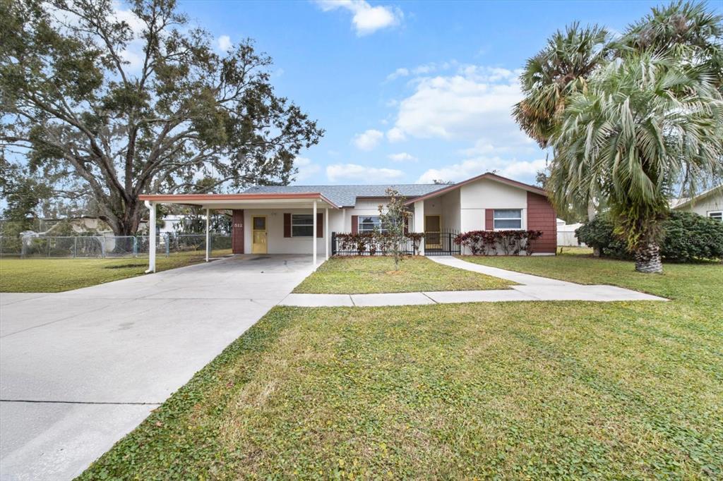 A single-story house features a carport, a concrete driveway, and a front lawn with trees — 512 PARADISE POINT, CRYSTAL RIVER, FL