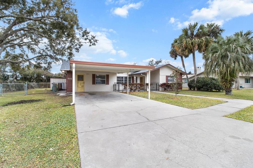 A single-story house features a concrete driveway, a carport, and a front yard with palm trees — 512 PARADISE POINT, CRYSTAL RIVER, FL