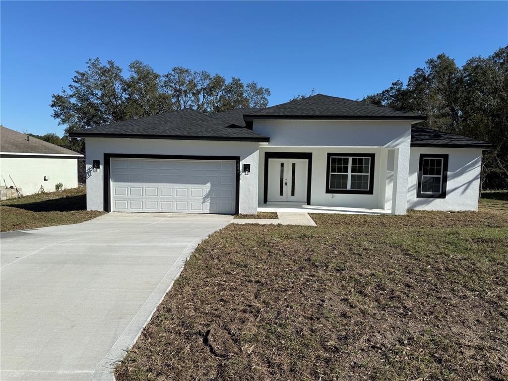 A single-story white house with a black roof, dark trim, and a two-car garage — 7897 N FIELDSTONE DRIVE, CITRUS SPRINGS, FL