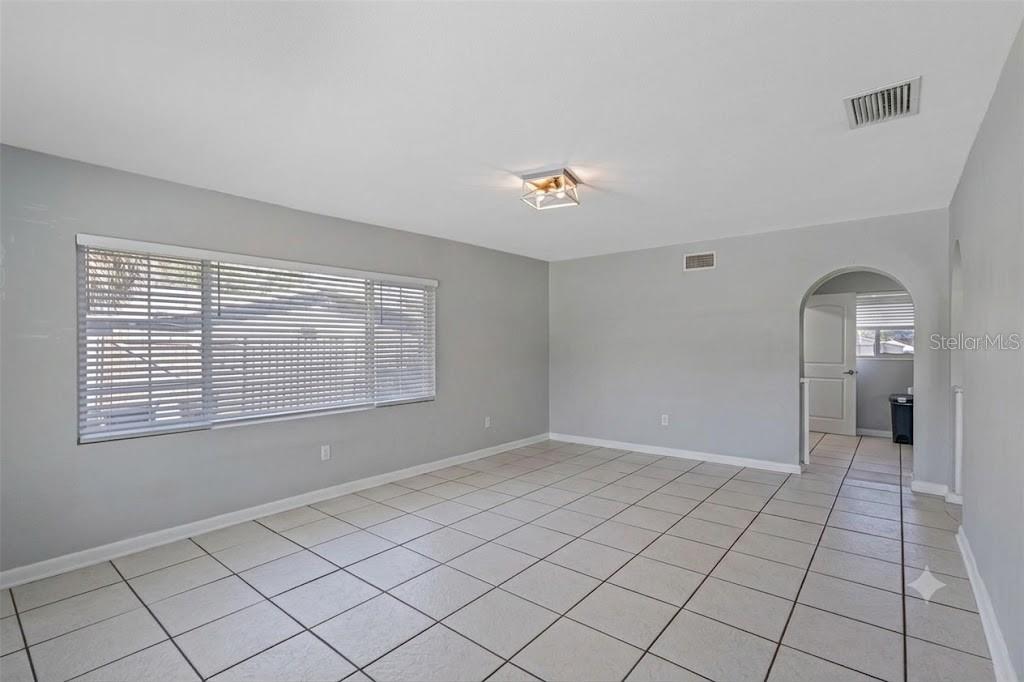 An empty room with light gray walls, white tile flooring, and two large windows — 605 S FLORIDA AVENUE, TARPON SPRINGS, FL