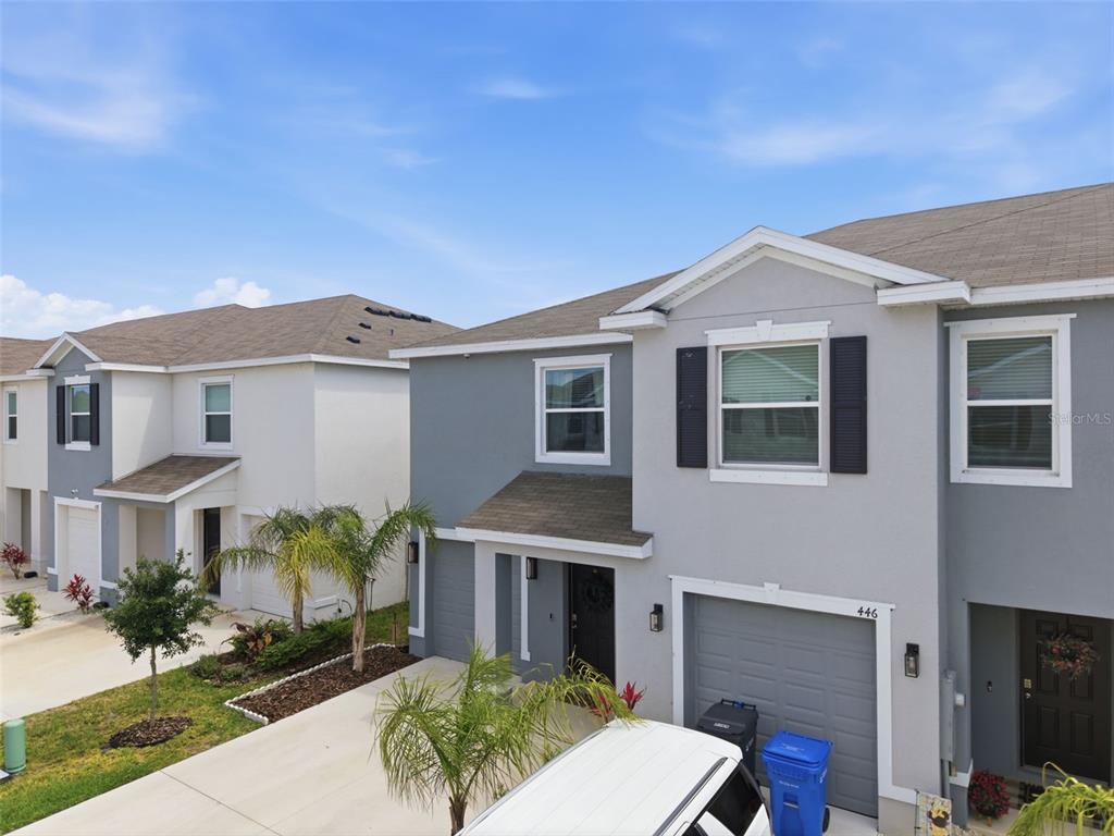 An exterior view of two-story townhomes with gray and white siding and attached garages — 444 MANGROVE SHADE CIRCLE, APOLLO BEACH, FL