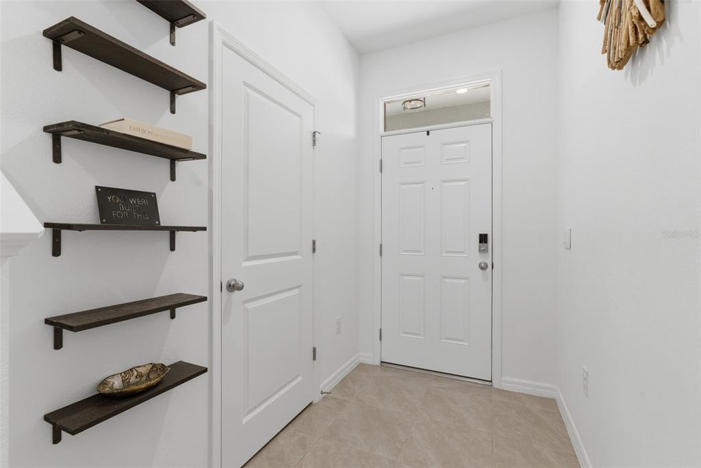 An entryway features a white front door, tiled flooring, and a wall with floating shelves — 444 MANGROVE SHADE CIRCLE, APOLLO BEACH, FL