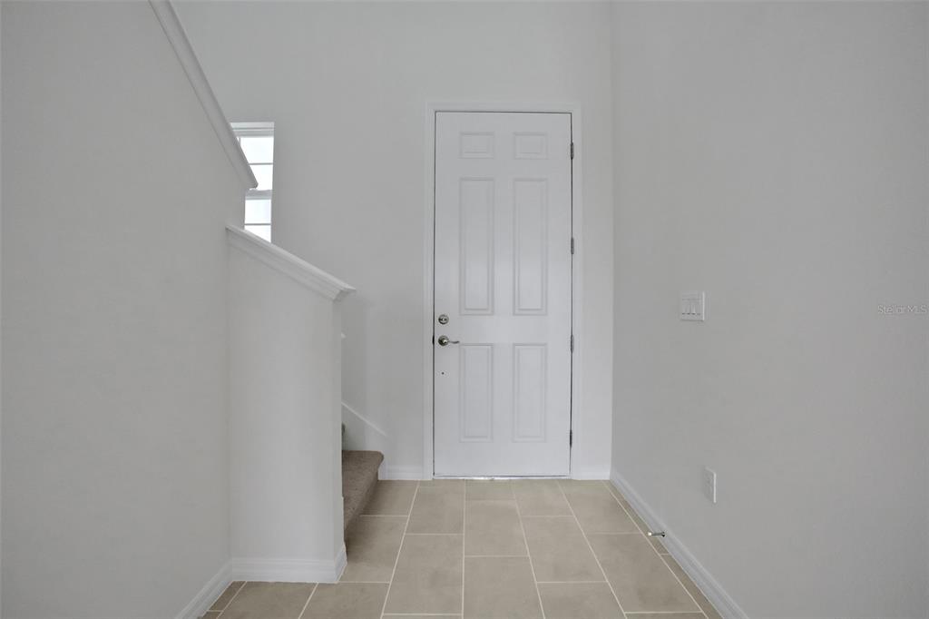 An entryway features a white door, tiled flooring, and a staircase with carpeted steps — 13485 TURNLEAF BOULEVARD, PUNTA GORDA, FL
