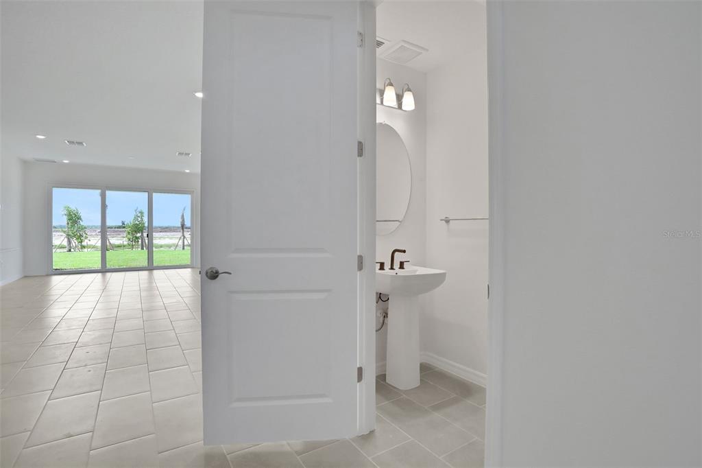 A view through an open doorway into a small bathroom with a pedestal sink — 13485 TURNLEAF BOULEVARD, PUNTA GORDA, FL