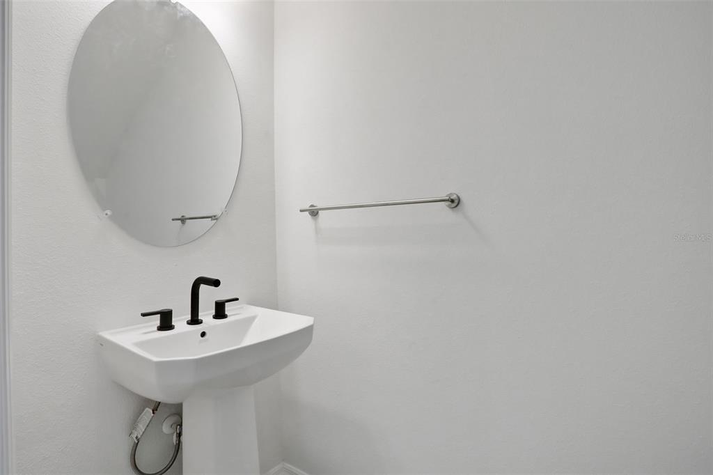 A white pedestal sink with a black faucet sits below an oval mirror — 13485 TURNLEAF BOULEVARD, PUNTA GORDA, FL