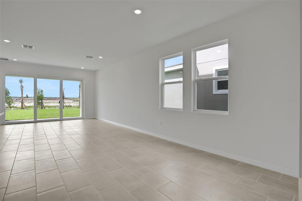 An empty room with light-colored tile flooring, white walls, recessed lighting, and large windows — 13485 TURNLEAF BOULEVARD, PUNTA GORDA, FL