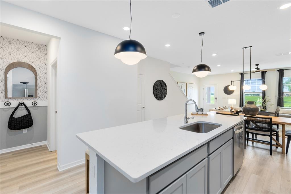 A kitchen island with a white countertop and grey cabinets sits before a dining area — 10682 EVENING STAR STREET, ORLANDO, FL