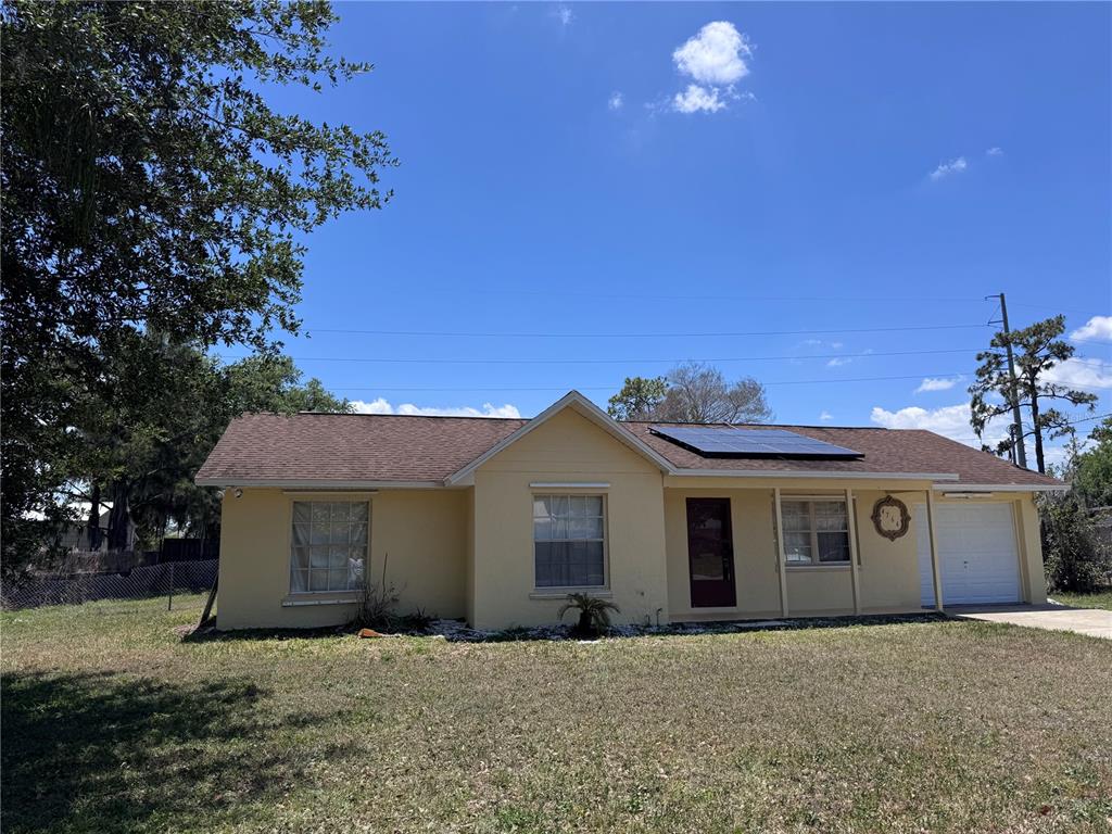A single-story yellow house with a brown roof, solar panels, and an attached garage — 4764 MALLARD DRIVE, ST CLOUD, FL