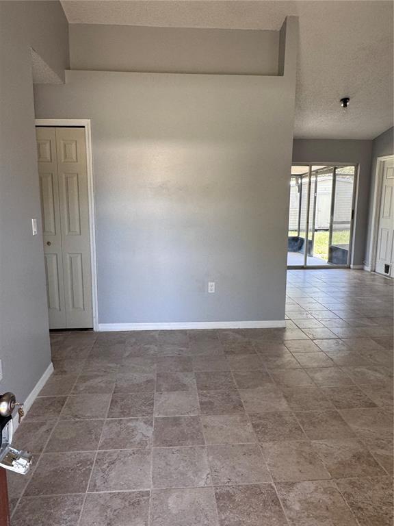An interior view shows a room with gray walls, tiled flooring, and a sliding glass door — 4764 MALLARD DRIVE, ST CLOUD, FL