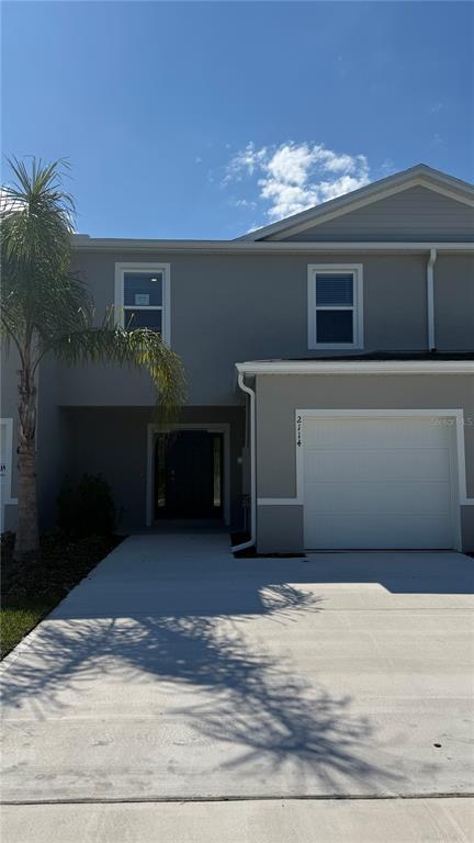 A two-story townhouse exterior features a gray facade, a single-car garage, and a palm tree — 2114 GENTLE RAIN DRIVE, EDGEWATER, FL