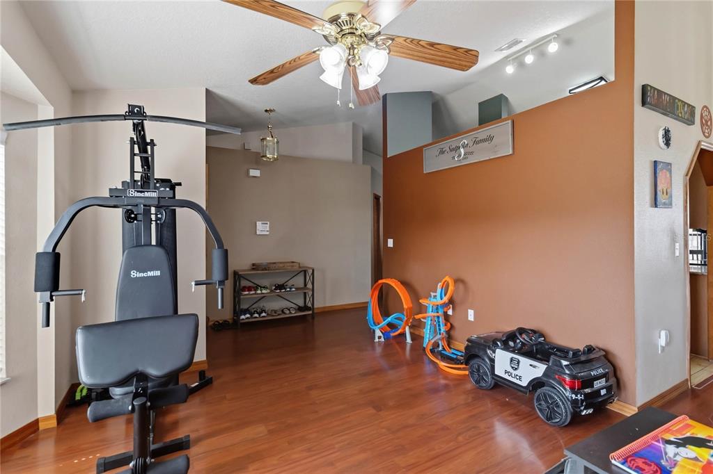 A room with hardwood floors, a ceiling fan, a home gym machine, and children's toys — 2207 DEATA COURT, ST CLOUD, FL