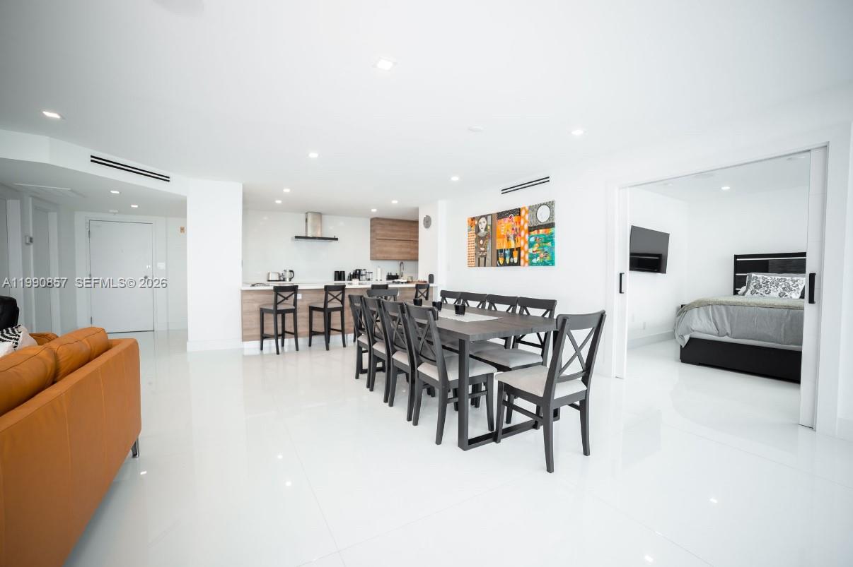 An open-concept living and dining area features white tile floors and a modern kitchen — 5600 Collins Ave # 14K, Miami Beach FL 33140, MIAMI BEACH, FL