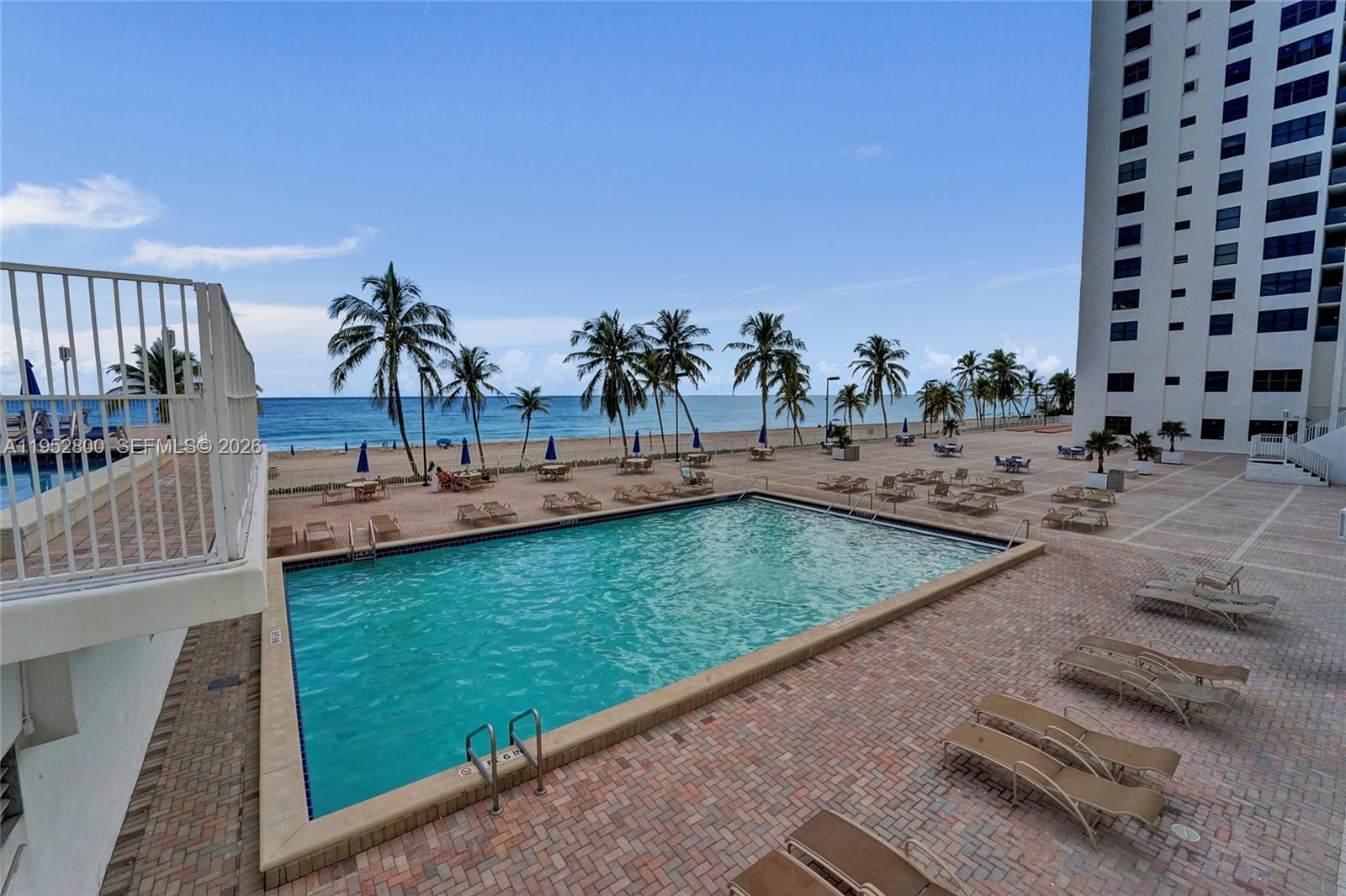 An outdoor swimming pool is surrounded by a brick patio, lounge chairs, and palm trees — 2201 S Ocean Dr # 608, Hollywood FL 33019, HOLLYWOOD, FL