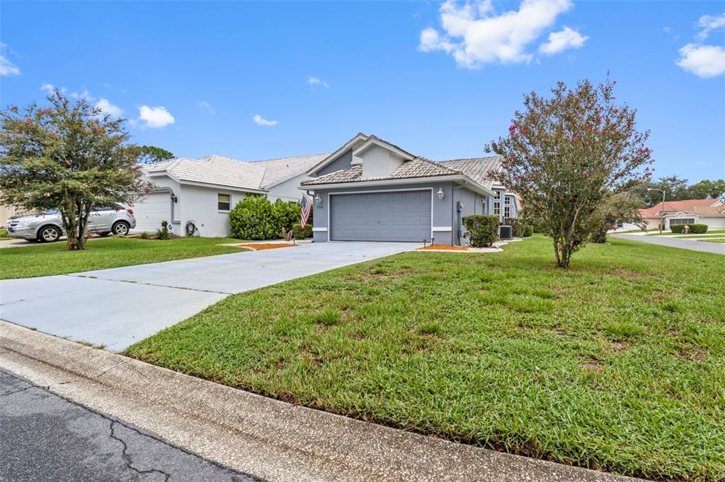 A single-story house with a gray garage and a concrete driveway under a blue sky — 9288 NEW ORLEANS DRIVE, WEEKI WACHEE, FL