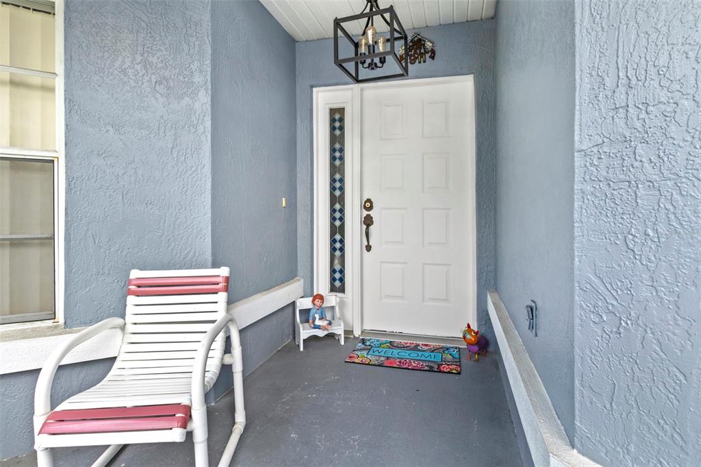 A covered front porch features a white door, a rocking chair, and a welcome mat — 9288 NEW ORLEANS DRIVE, WEEKI WACHEE, FL