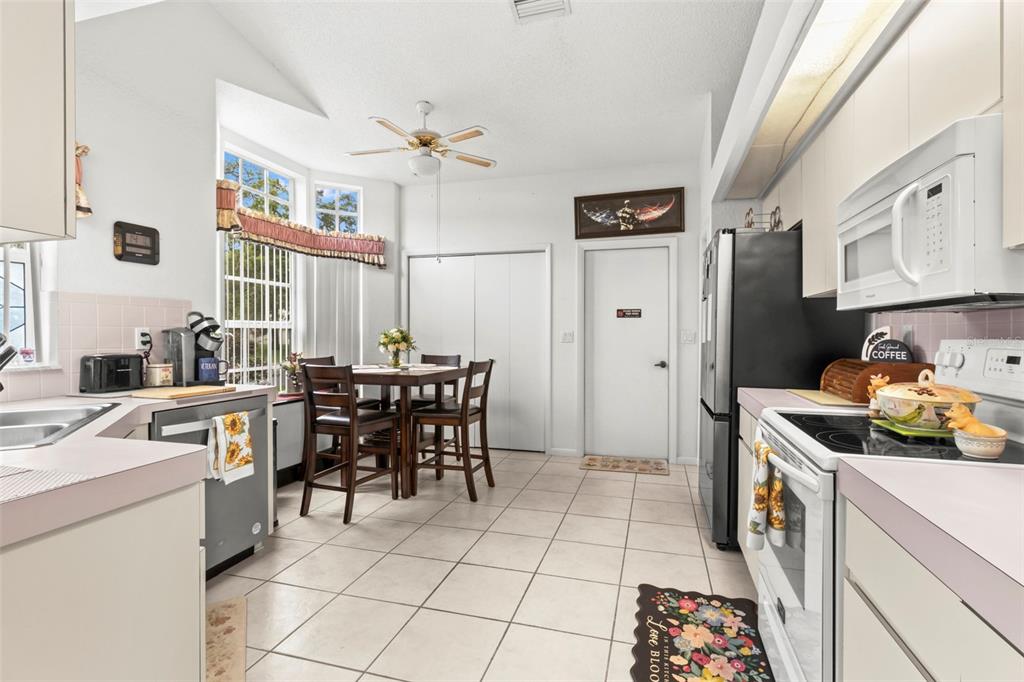 A kitchen with white cabinets, tile flooring, a dining area, and a ceiling fan — 9288 NEW ORLEANS DRIVE, WEEKI WACHEE, FL